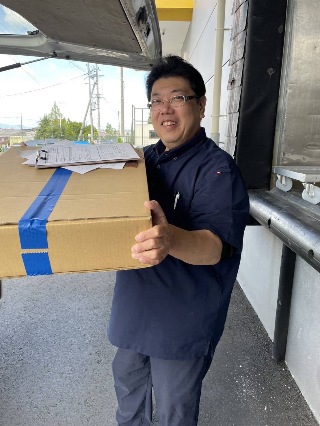 弁当配送（企業配）。配送車から荷物を降ろすこころ物流のドライバー